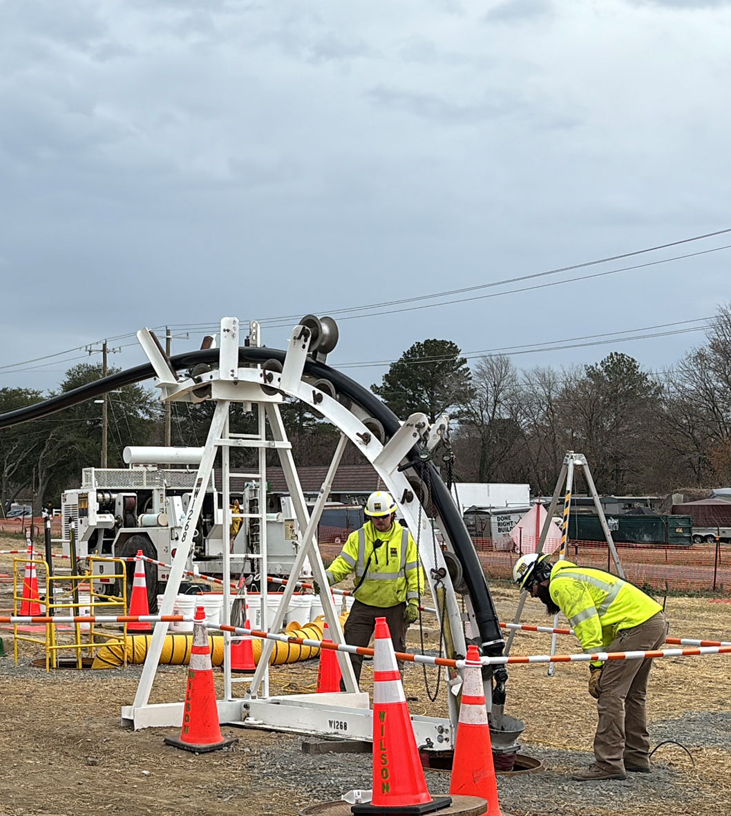 Two workers in safety jackets oversee onshore transmission construction