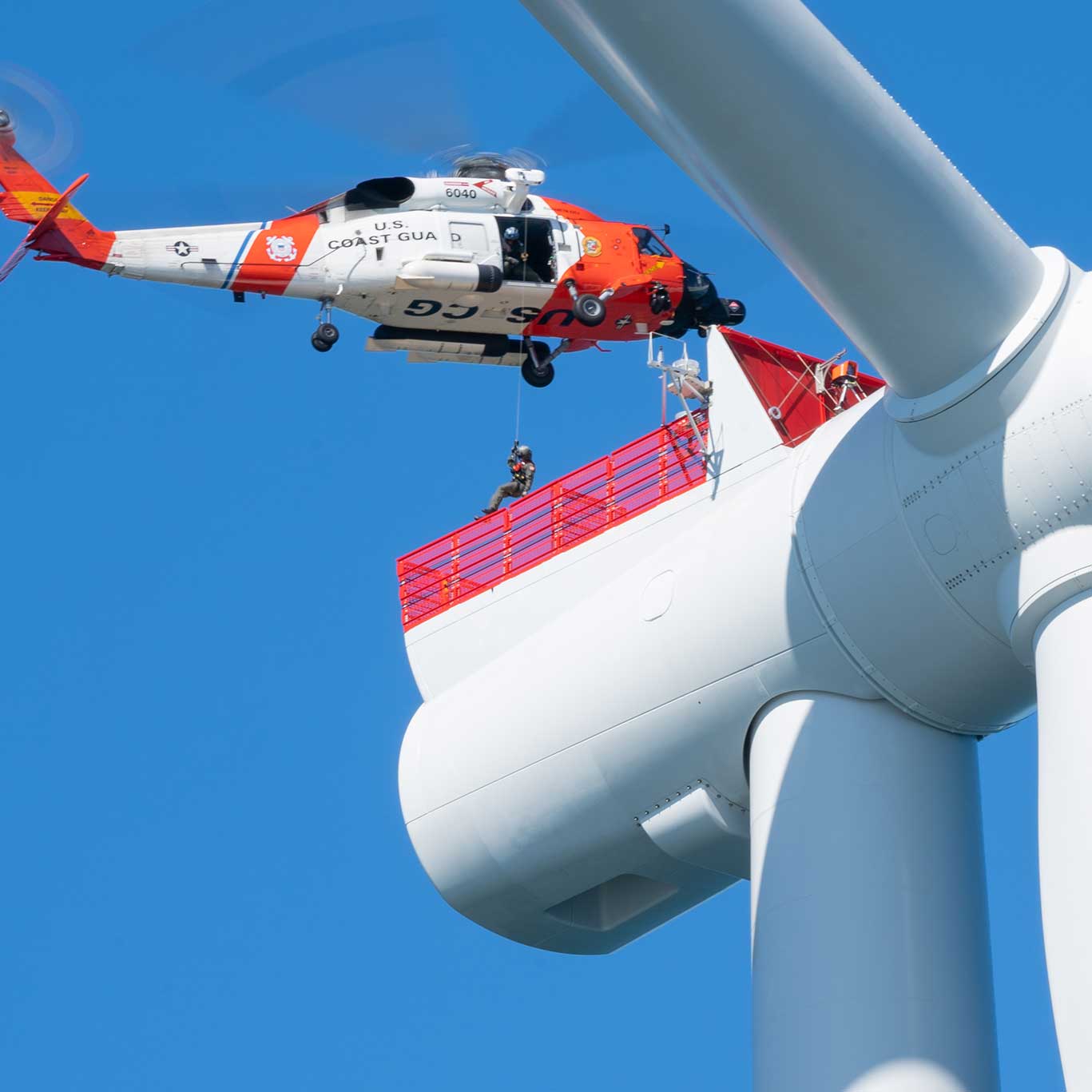 U.S. Coast Guard helicopter conducts a training exercise on a wind turbine