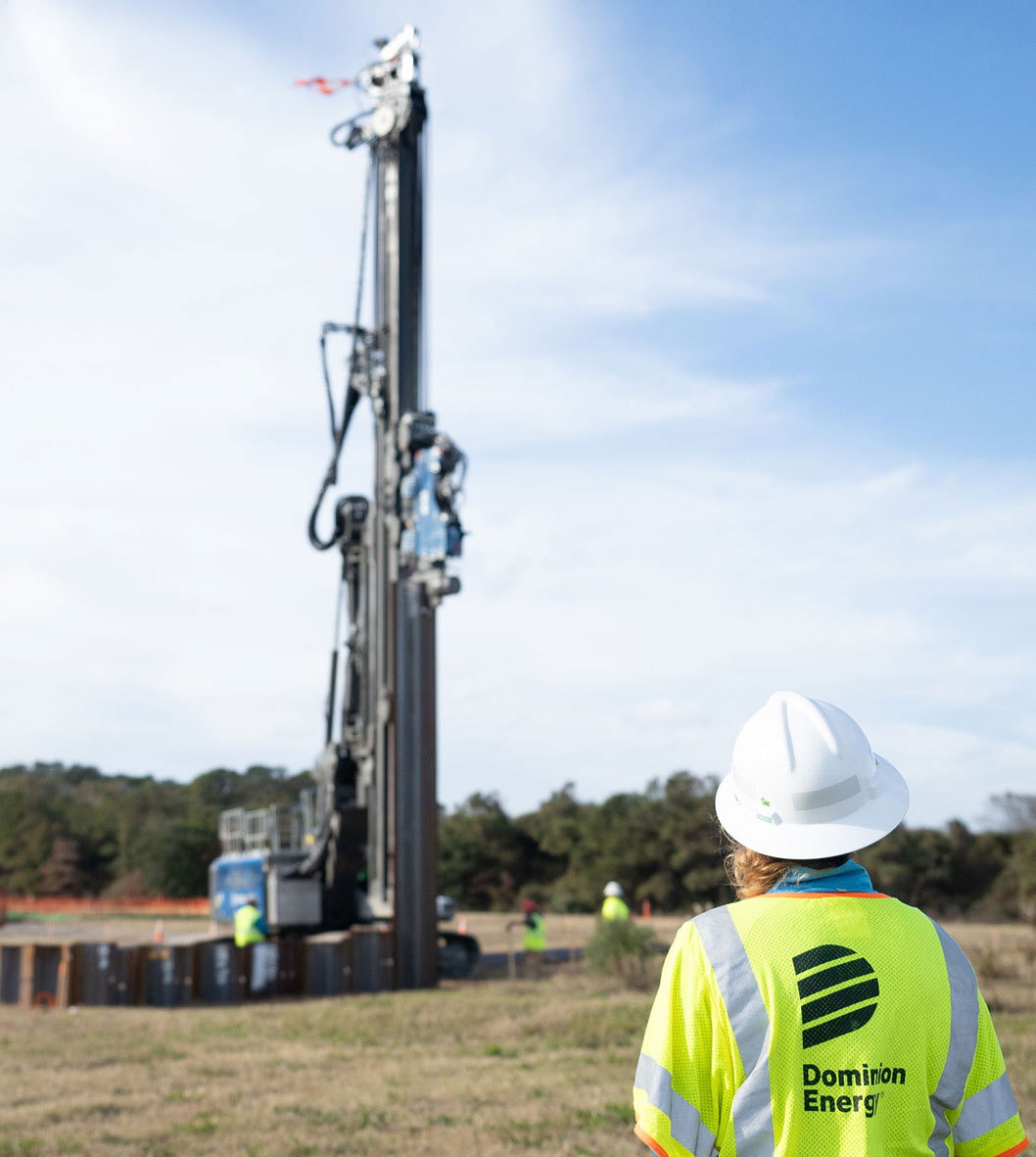 Dominion Energy worker in a safety vest watches the underground construction take place