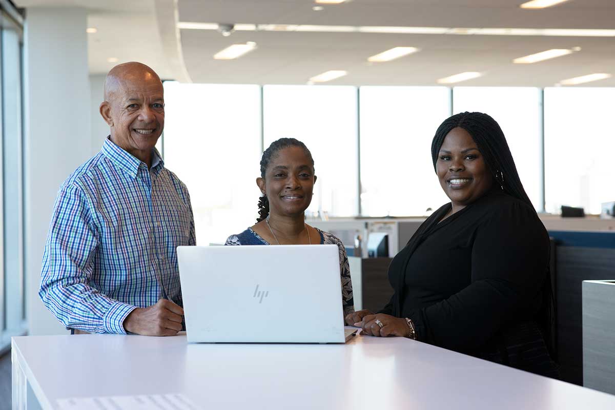 Group of coworkers standing in front of computer