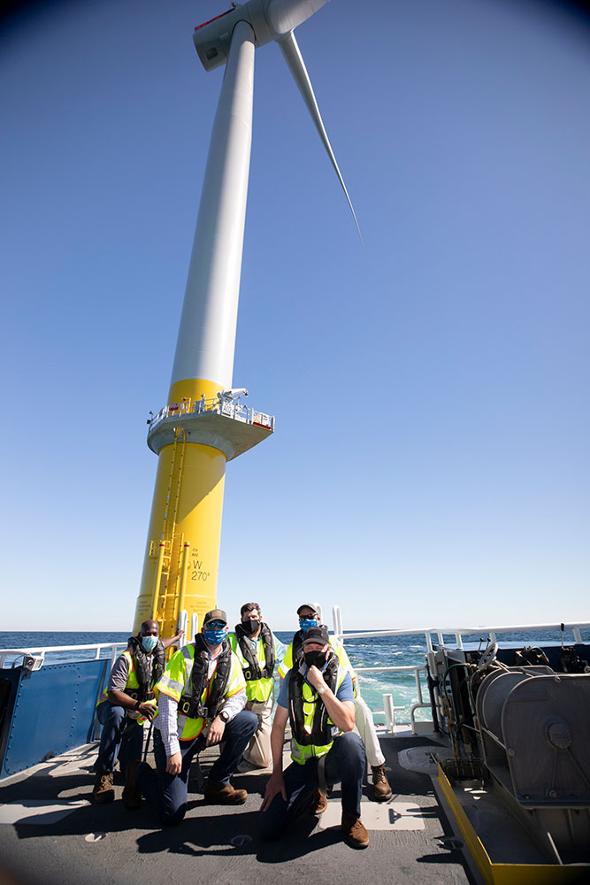 Workers pose at the base of the CVOW pilot turbine offshore